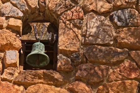 Téléchargez les photos : Une cloche de mission patinée posée dans un vieux mur de pierre de roches rougeâtres à l'Arboretum Boyce Thompson, Arizona. - en image libre de droit
