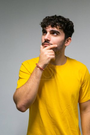 Foto de Blanco caucásico chico con pelo rizado y amarillo camiseta reflexivo sobre aislado blanco color fondo - Imagen libre de derechos