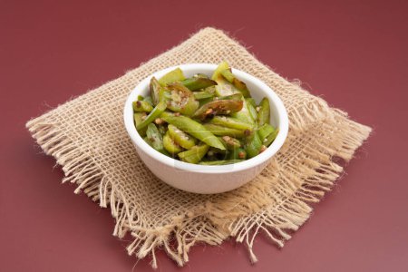 Téléchargez les photos : Grilled okra, in a white bowl on a wooden table, red background - en image libre de droit