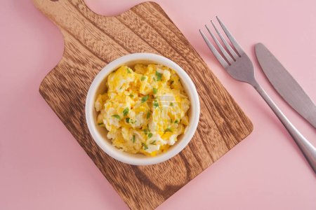 Scrambled eggs on bowl, pink background, top view-stock-photo