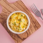 Scrambled eggs on bowl, pink background, top view
