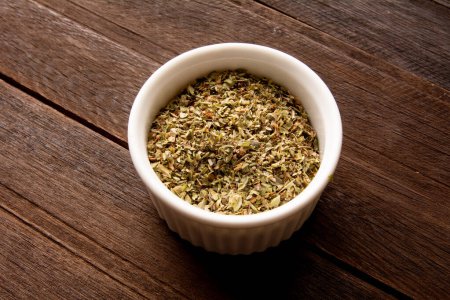 Photo for White ramekin with dry oregano above a real wooden table - Royalty Free Image