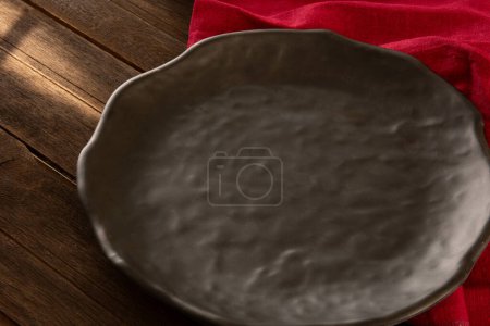 Foto de Un plato negro con tela roja encima de una maqueta de mesa de madera - Imagen libre de derechos