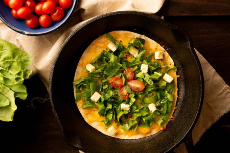 Photo for Cheesy Arugula Pizza with Cherry Tomatoes in Cast Iron Skillet in cropped front view - Royalty Free Image