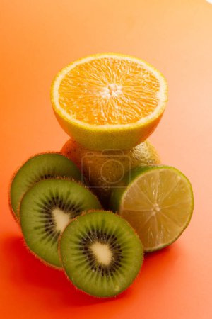 Téléchargez les photos : Composition de tranches d'orange, citron et kiwi fruits dans un fond orange propre en vue de face - en image libre de droit