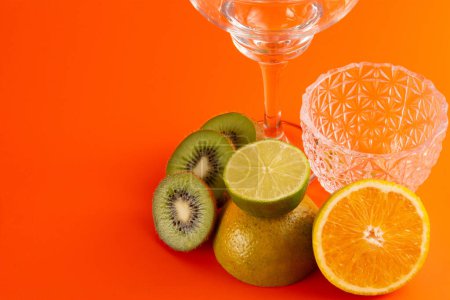 Téléchargez les photos : Composition de tranches d'orange, citron et kiwi fruits dans un fond orange propre en vue de face - en image libre de droit