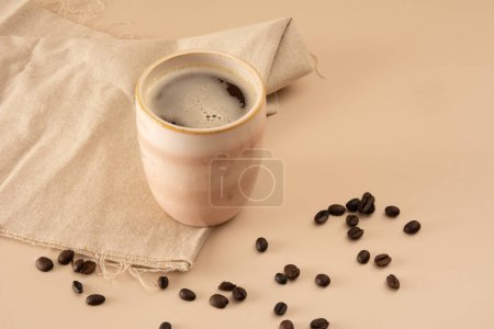 Coffee mug in a beige background with coffee beans and table cloth in aerial view