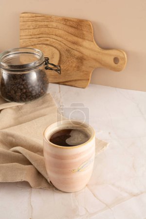 Coffee mug in a marbled stone background with beige napkin in front view
