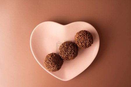 Foto de Bolas de trufa de chocolate Brigadeiro caramelo brasileño y hojuelas de chocolate vista aérea corazón bowl - Imagen libre de derechos