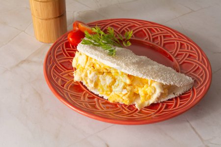 Tapioca Pancake with eggs Brazilian manioc food in top front view red plate clean background