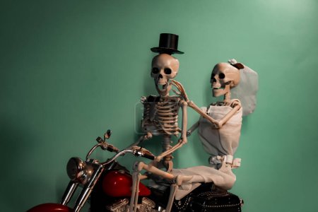 Photo for Happily married skeleton couple taking a photo on a motorcycle - Royalty Free Image