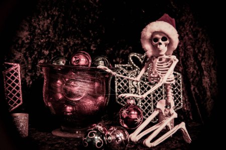 Foto de Invierno 2022 - Esqueleto con sombrero de Santa está clasificando bolas de adorno de Navidad - Imagen libre de derechos