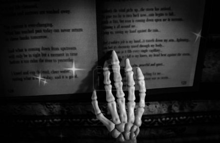 Foto de This skeleton is using thier fingers to outline the words being read in an old spell book. - Imagen libre de derechos