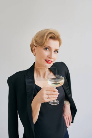 Téléchargez les photos : Mature stylish elegant woman in tuxedo with glass of sparkling wine. Party, celebration, anti age concept - en image libre de droit