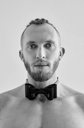 Téléchargez les photos : Portrait monochrome de beau jeune homme athlétique caucasien seins nus en noeud papillon en cuir. Fitness, bodybilding - en image libre de droit
