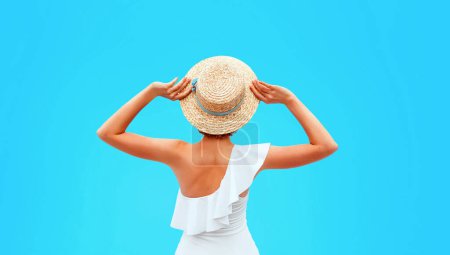Photo for Fit caucasian woman's back in the white swimminig suit sitting by the swimming pool (or sea or ocean) in the straw hat in summer day. Summer, relax, wellness, recreation concept - Royalty Free Image