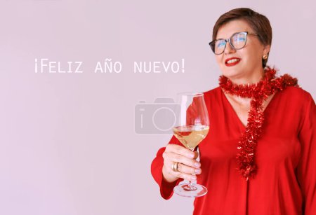Téléchargez les photos : Élégante femme âgée mature en chemisier rouge avec un verre de vin blanc célébrant le nouvel an. Fun, fête, style de vie, alcool, concept de célébration - en image libre de droit