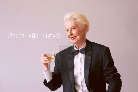 Foto de Mujer mayor madura con estilo en esmoquin con copa de vino espumoso que celebra el Año Nuevo. Diversión, fiesta, estilo, estilo de vida, alcohol, concepto de celebración - Imagen libre de derechos