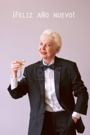 Foto de Mujer mayor madura con estilo en esmoquin con copa de vino espumoso que celebra el Año Nuevo. Diversión, fiesta, estilo, estilo de vida, alcohol, concepto de celebración - Imagen libre de derechos