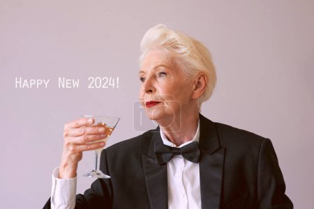 Téléchargez les photos : Élégante femme âgée mature en smoking avec un verre de vin mousseux célébrant le Nouvel An. Fun, fête, style de vie, alcool, concept de célébration - en image libre de droit