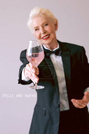 Téléchargez les photos : Élégante femme âgée mature en smoking avec un verre de vin mousseux célébrant le Nouvel An. Fun, fête, style de vie, alcool, concept de célébration - en image libre de droit