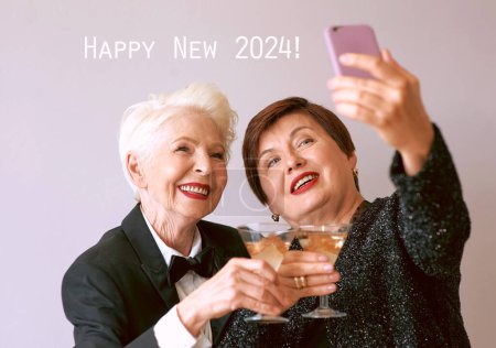 Téléchargez les photos : Deux belles femmes âgées matures élégantes buvant du vin et faisant selfie photo. Fun, fête, technologie, style, concept de célébration - en image libre de droit