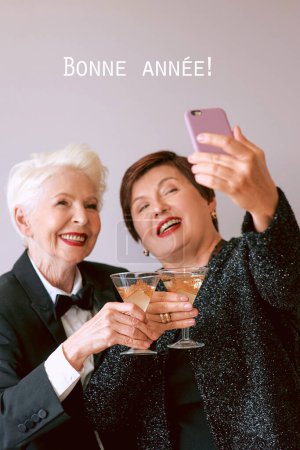 Photo for Two beautiful stylish mature senior women drinking wine and making selfie photo. Fun, party, technology, style, celebration concept - Royalty Free Image