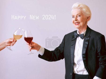 Téléchargez les photos : Sommelier senior élégant femme en smoking avec verre ou vin rouge à la fête. Boisson, mature, style, concept d'amitié - en image libre de droit
