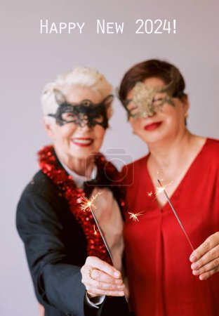 Foto de Dos hermosas mujeres maduras maduras elegantes en máscaras de carnaval con destellos que celebran el año nuevo. Diversión, fiesta, estilo, concepto de celebración - Imagen libre de derechos
