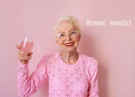 Foto de Mujer mayor caucásica feliz en suéter rosa cachemira beber rosa sobre fondo rosa. Celebración, amor, jubilación, concepto maduro - Imagen libre de derechos