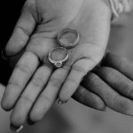 a pair of rings on the hands of the bride and groom in a black and white photo