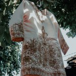 The bride's traditional dress is hanging on a tree branch
