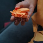 a child's hand holding a macaron
