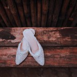 Close-up of a pair of white wedding shoes on a rustic wooden bench