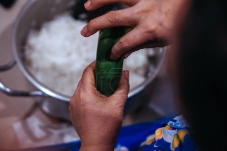 Closeup of hands making lontong wrapped in banana leaves