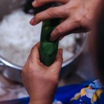 closeup of hands making lontong wrapped in banana leaves