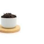 Dry black tea in round bowl isolated on white background