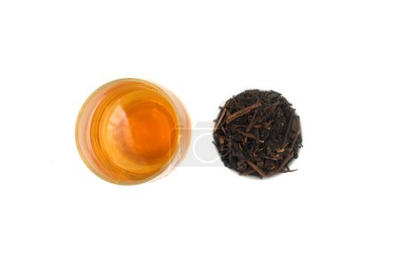 a glass of tea and a small cup of black tea leaves next to it