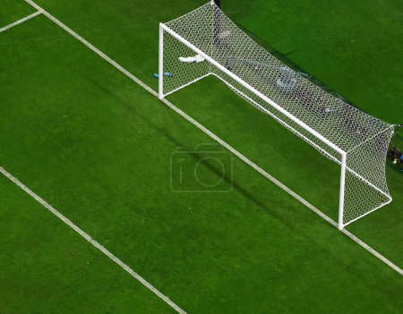 Photo for Green football pitch goal post from top view. Football goal with the white mesh on a green lawn in the evening background - Royalty Free Image