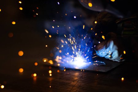 Metallschweißer arbeitet mit einem Stahlschweißer in einer Fabrik mit Schutzausrüstung. Herstellung von Metallkonstruktionen und Reparatur- und Baudienstleistungen nach dem Konzept der Handarbeit.