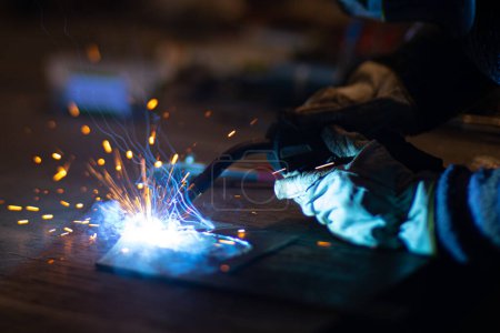 Soudeur de métaux travaille avec un soudeur d'acier dans une usine avec un équipement de protection. Fabrication de structures métalliques et services de réparation et de construction selon le concept de travail manuel.