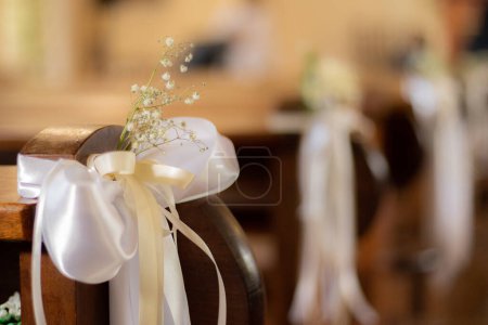 Photo for The church benches are decorated with a bouquet of flowers and a white ribbon. Soft selective focus. Artificially created grain for the picture - Royalty Free Image