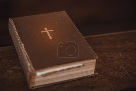 Foto de La Biblia en el banco de la iglesia. La palabra de Dios en un pequeño libro. Enfoque selectivo suave. Grano creado artificialmente para la imagen - Imagen libre de derechos