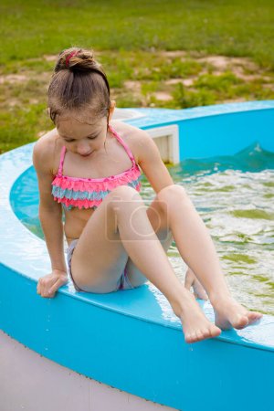 A little girl is swimming alone in the pool. A child by the pool of water. Child safety near water bodies