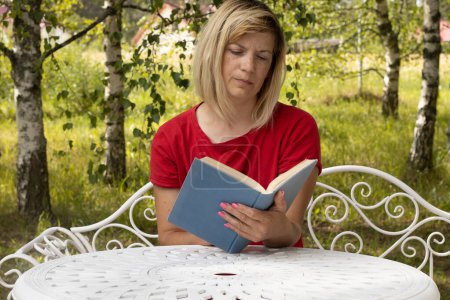 Foto de Una mujer con un libro en la mesa. Una mujer está leyendo un libro. Aprendizaje a distancia en casa - Imagen libre de derechos