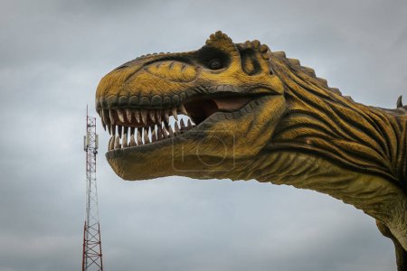 Foto de Una torre de comunicación con un dinosaurio en el fondo. Torre de señal con grandes precios. Un concepto con altas tasas de comunicación. - Imagen libre de derechos