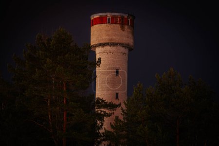 Photo for The water tower in the dark behind the pines - Royalty Free Image