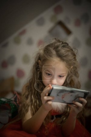 Photo for Child Concentration, Female Digital Native Looking Down Holding Technology. A concentrated female digital native looking down while holding technology. Soft selective focus - Royalty Free Image