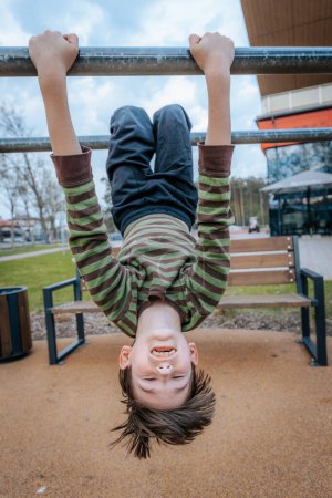 boy was hanging upside down on the bars. Smiling happy child
