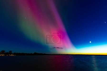 Luces boreales sobre el lago Burtnieks. Aurora Boreal o Northern Lights Letonia. Aurora reflejo en el agua por la noche